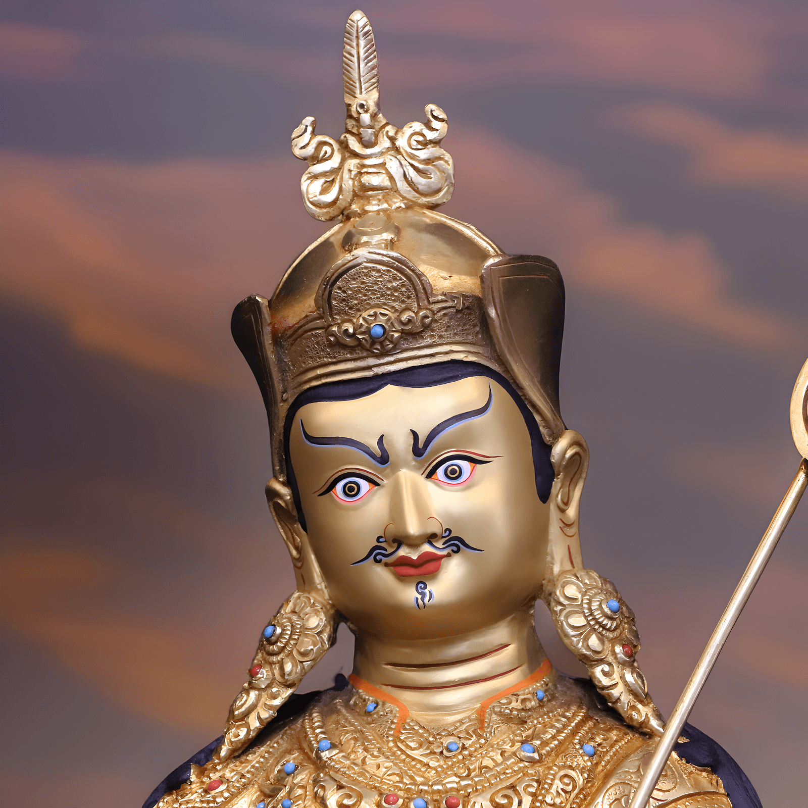 Nahaufnahme des Gesichts einer handbemalten Guru Rinpoche Statue (34 cm) mit Goldpigmenten.